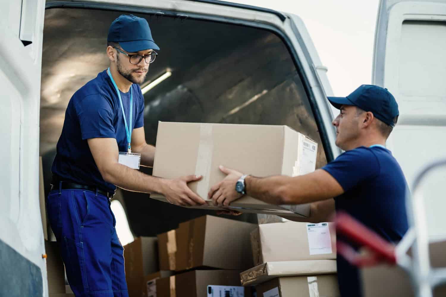 Two movers loading boxes into a van, showcasing professional moving services in Regina.